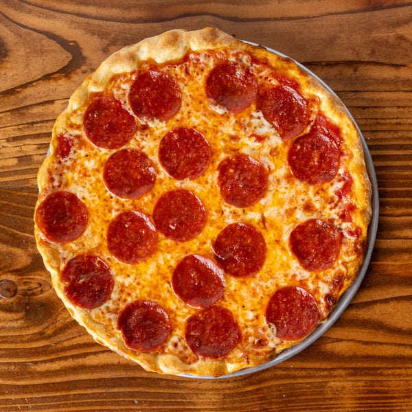 A freshly baked pepperoni pizza with a golden crust sits on a rustic wooden table.